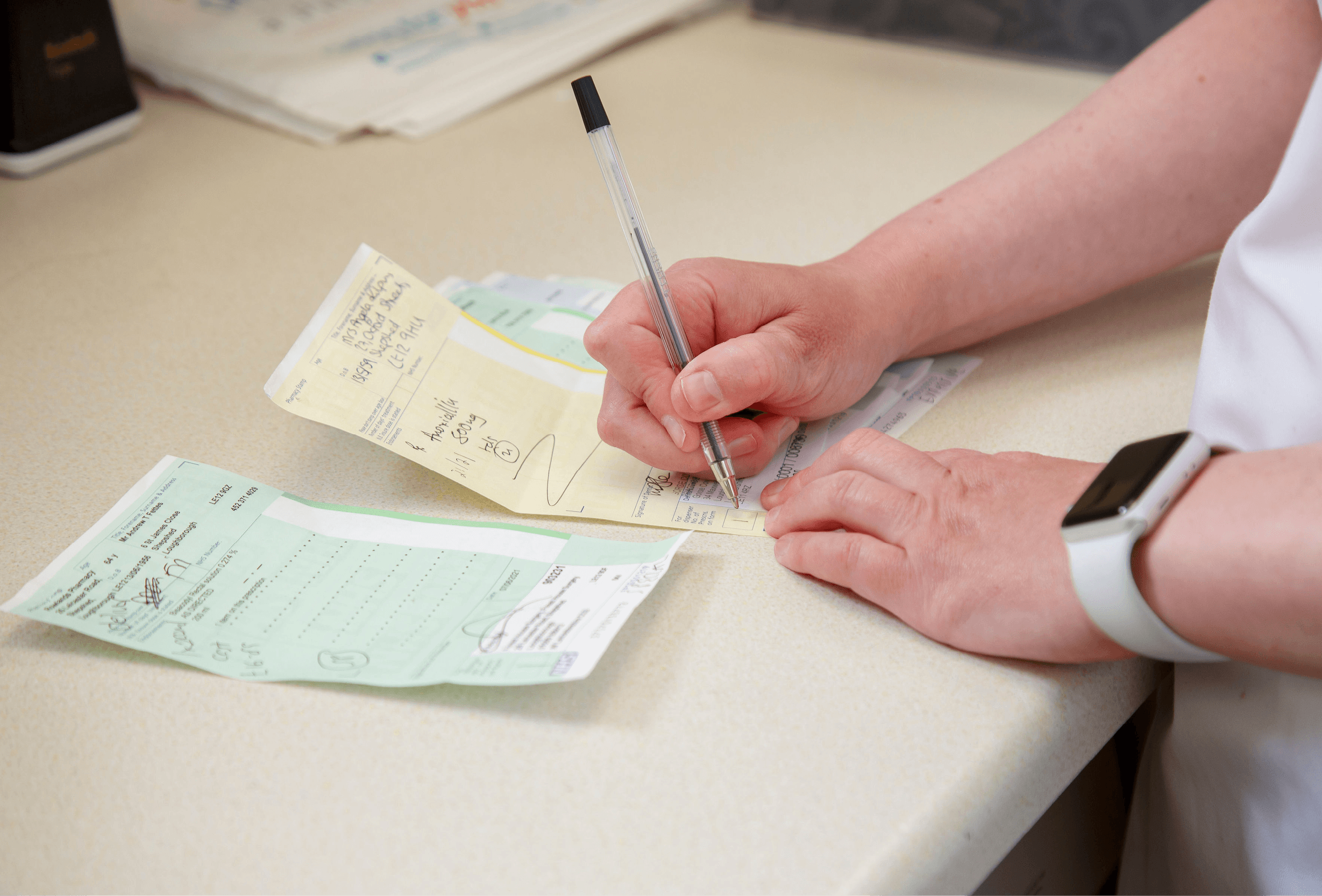 lady signing prescriptions at desk